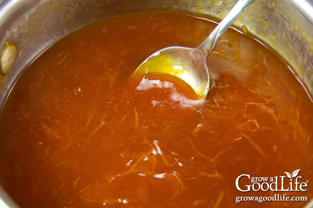 Orange sweet and sour sauce simmering in a saucepan.