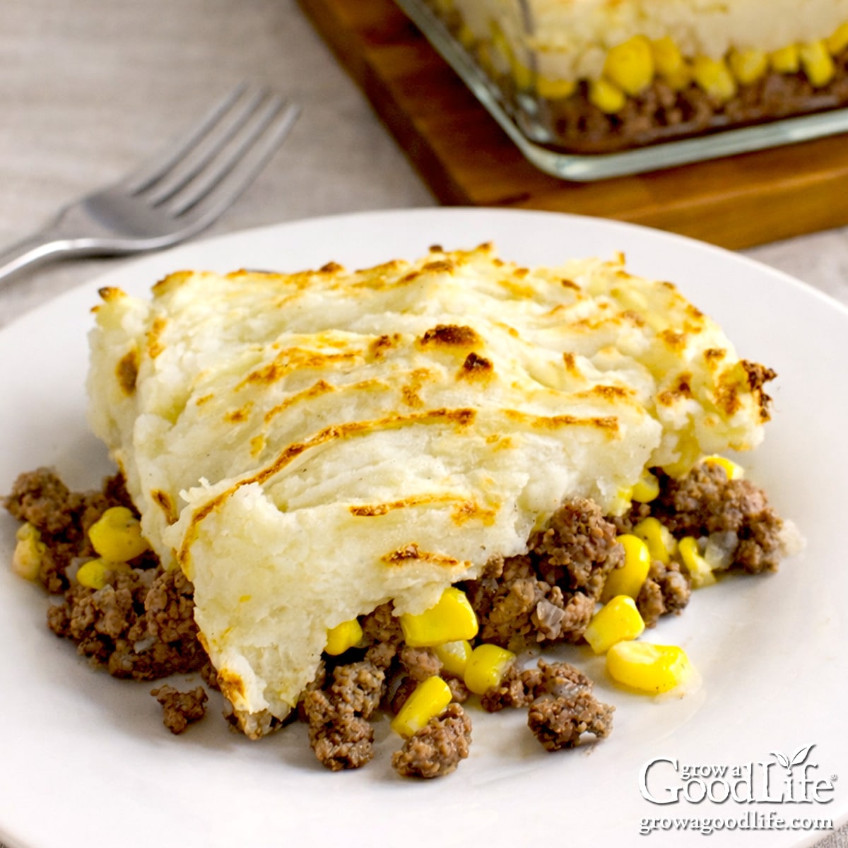Pâté chinois served on a white plate with layers of ground beef, corn, and golden mashed potatoes.