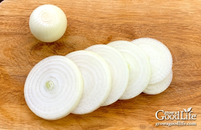 Sliced onions on a wooden cutting board.