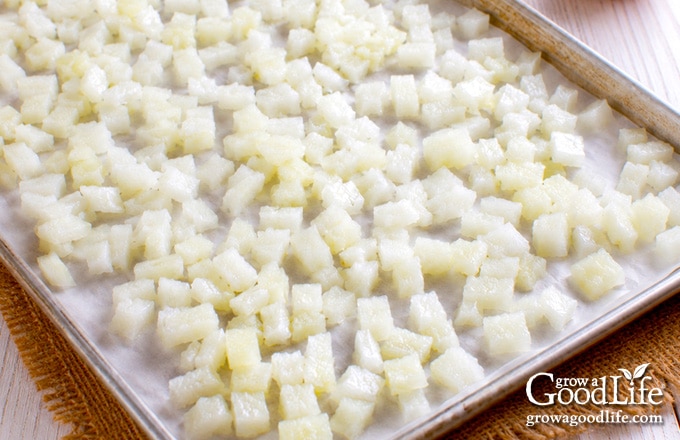 Chopped onions spread on a parchment-lined baking sheet for flash freezing.