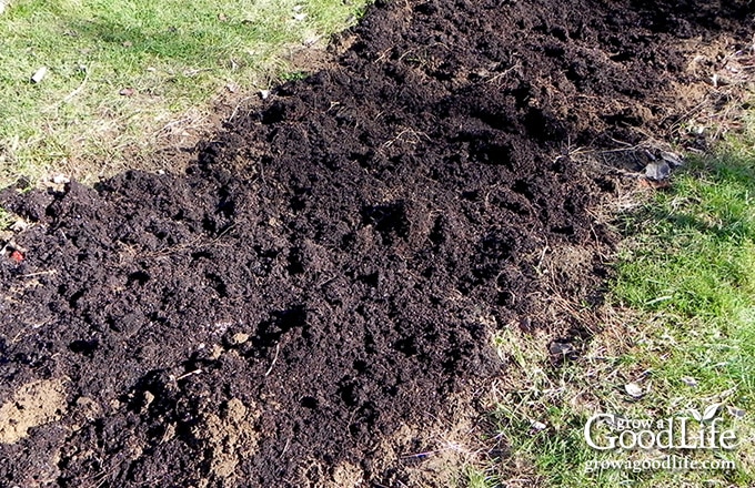 Compost added to sandy soil in an in-ground vegetable garden bed.