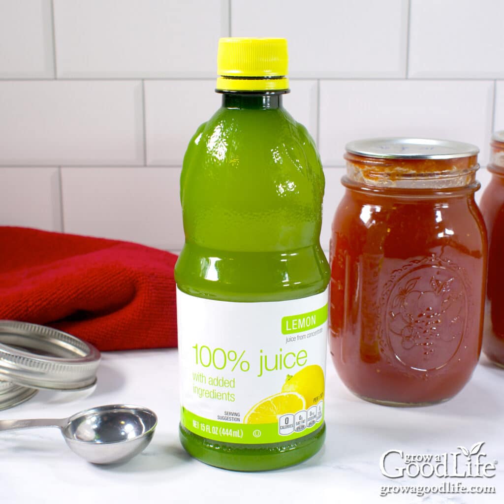 Bottle of lemon juice made from concentrate beside jars of home-canned tomato sauce.