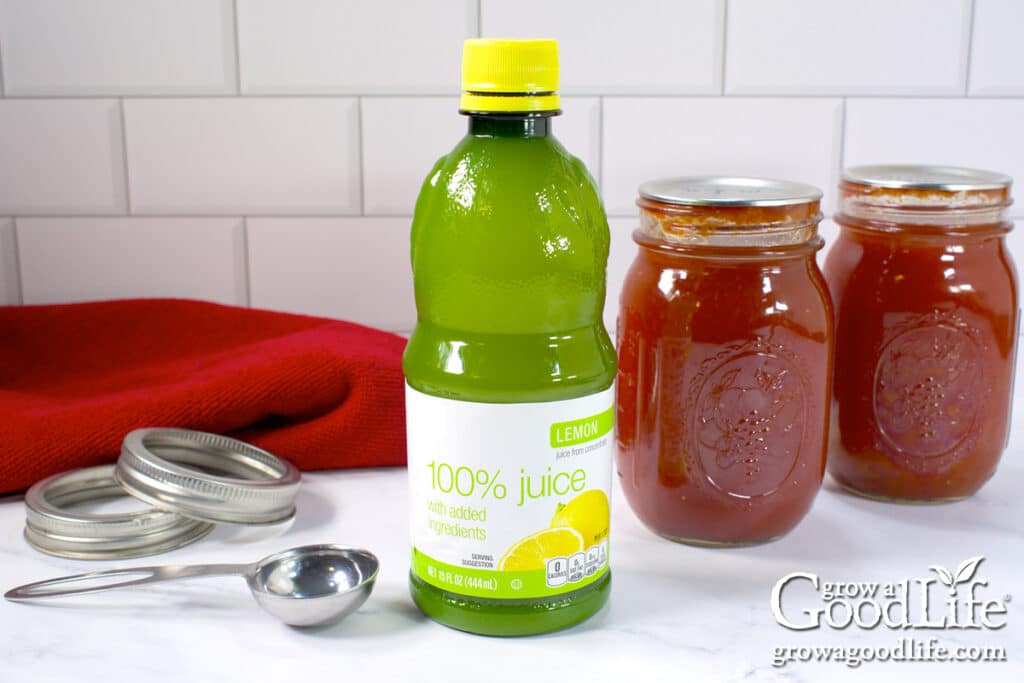 Bottle of lemon juice made from concentrate with pint jars of home-canned tomato sauce in the background.